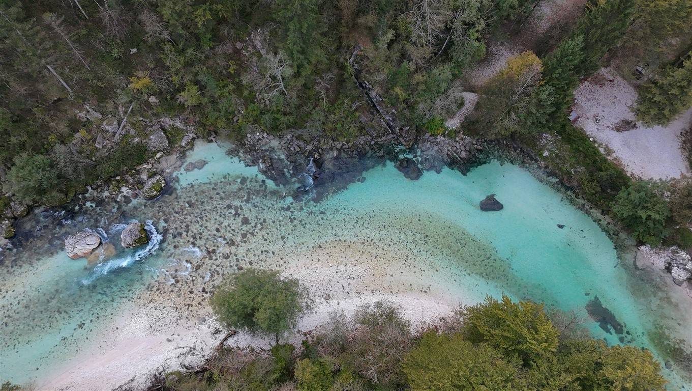 Aerial view of the turquoise Soča River flowing past the forest near Camp Vodenca in Bovec, Slovenia.